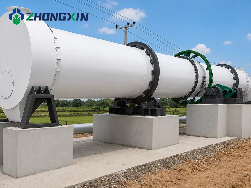 Large white single-drum dryer shell standing outdoors against a clear blue sky
