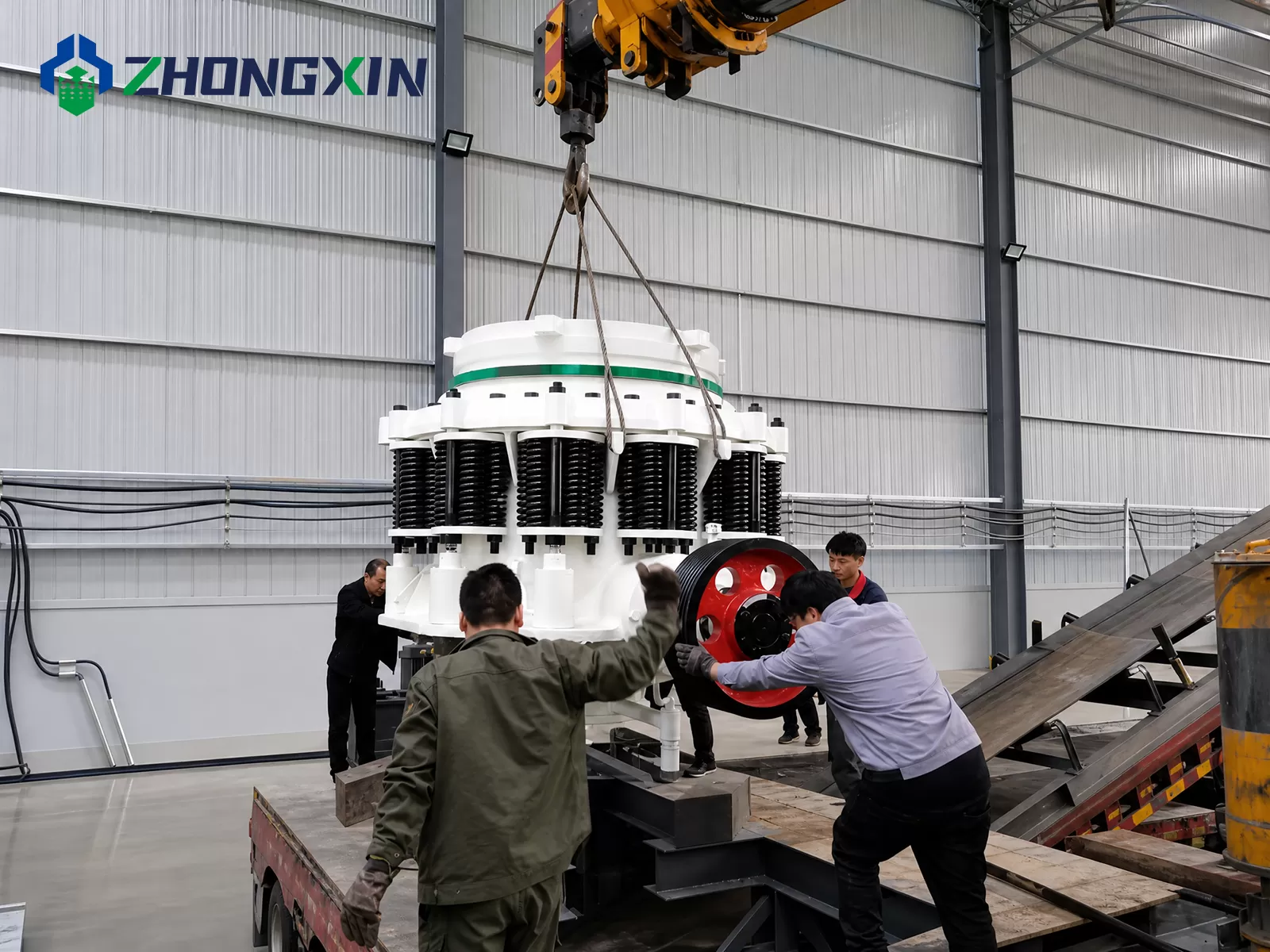 Crane lifting and assembling ZX compound cone crusher at factory workshop